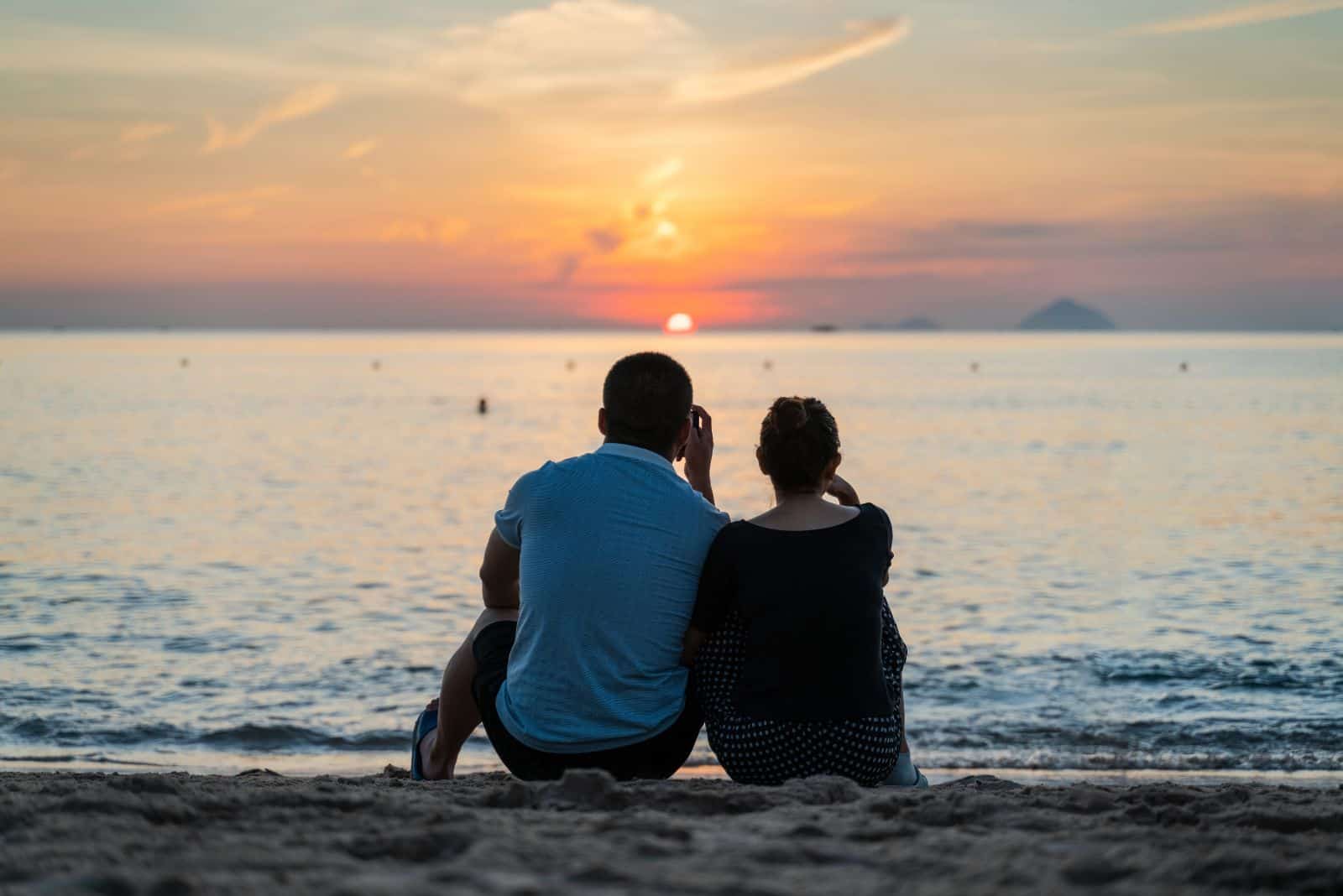 mies ja nainen istuvat rannalla