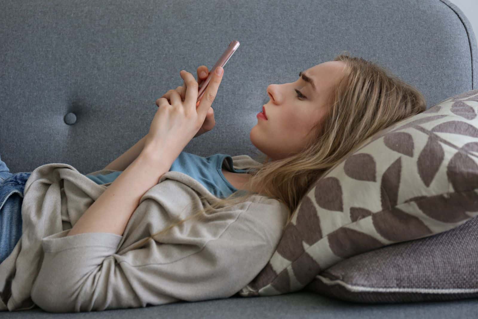 tyttö makaa sohvalla ja kirjoittaa puhelimeen