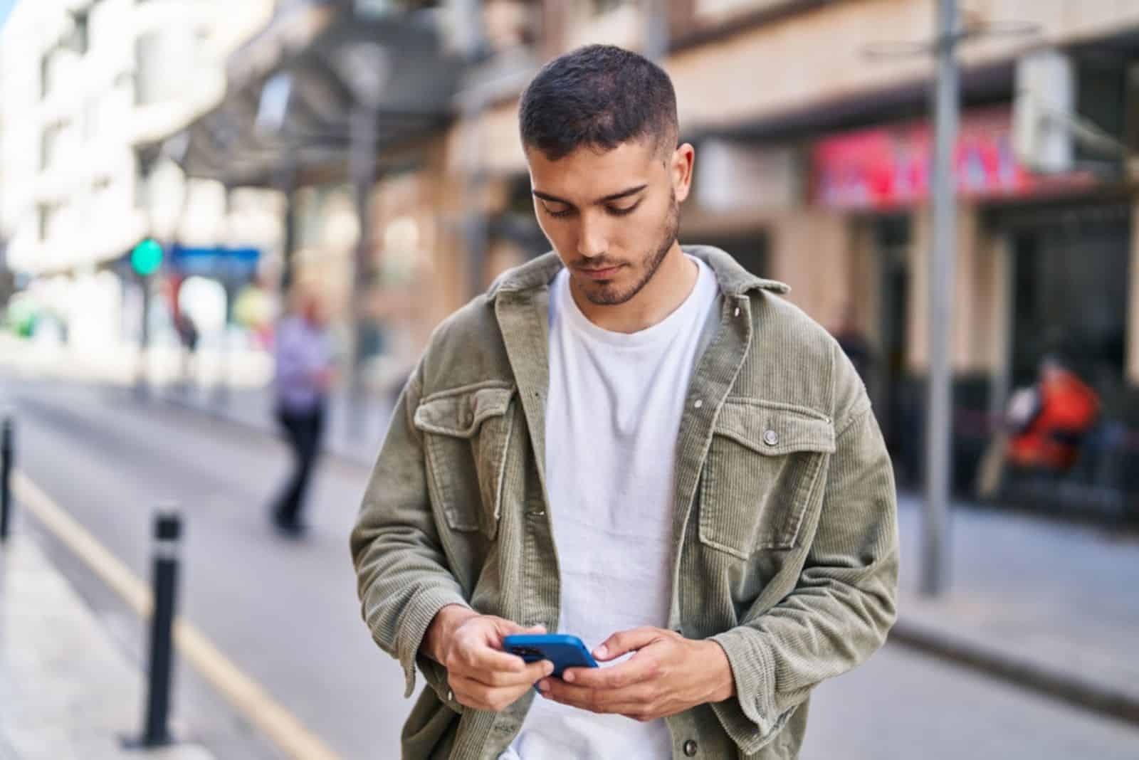 Nuori latinalaisamerikkalainen mies käyttää älypuhelinta kadulla