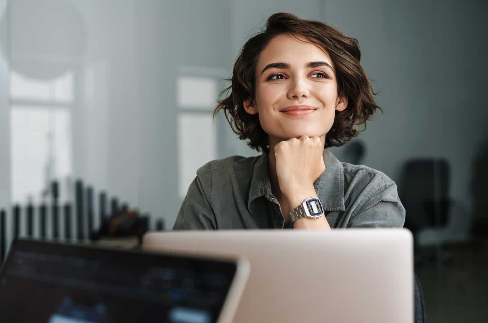 nuori nainen hymyilee kannettavalla tietokoneella