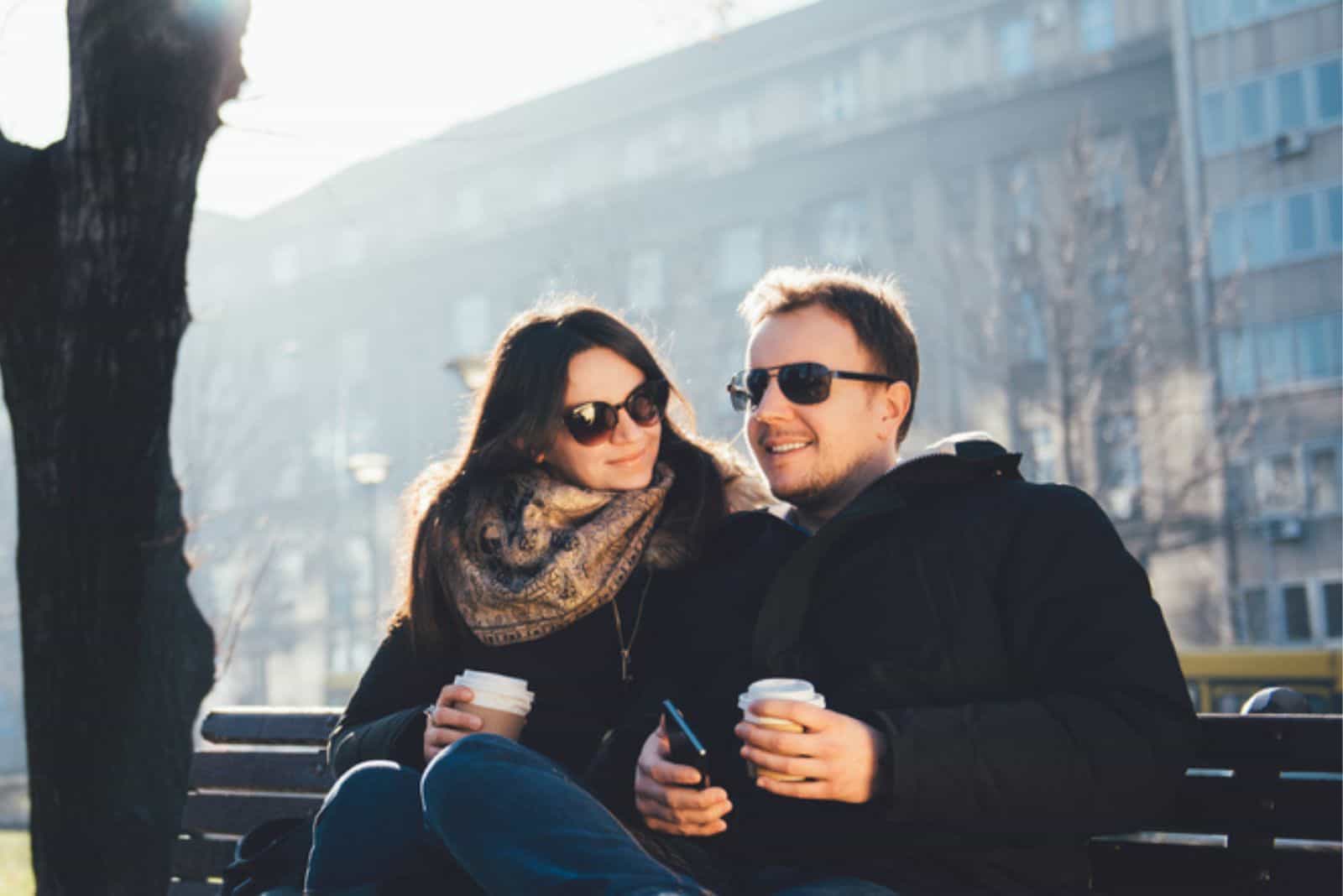 hymyilevä mies ja nainen istuvat puistossa ja puhuvat