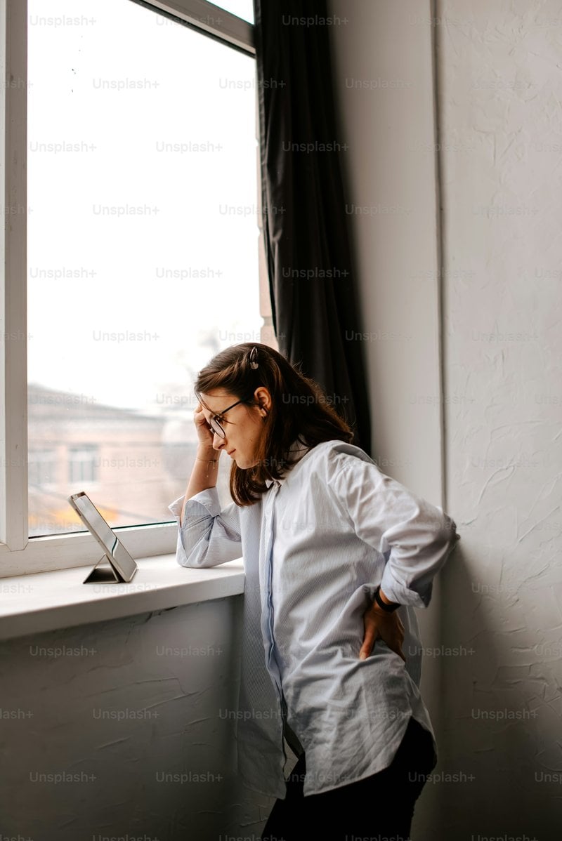 A woman leaning against a window sill while talking on a cell phone photo &ndash;  Technology Image on Unsplash