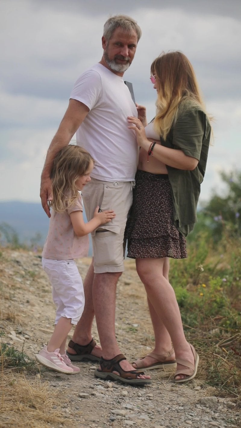A family standing on a dirt road with a sign that says, the best way to  raise a child