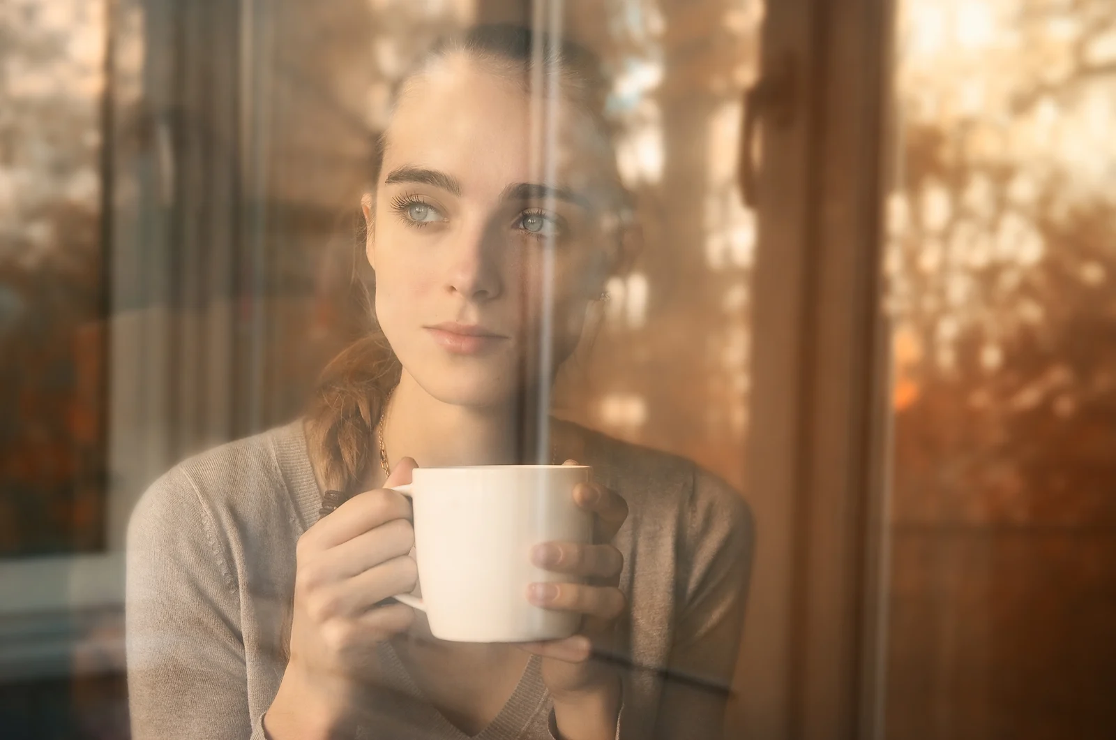 Traurige Frau, die Kaffee trinkt und aus dem Fenster schaut Traurige Frau, die Kaffee trinkt und aus dem Fenster schaut