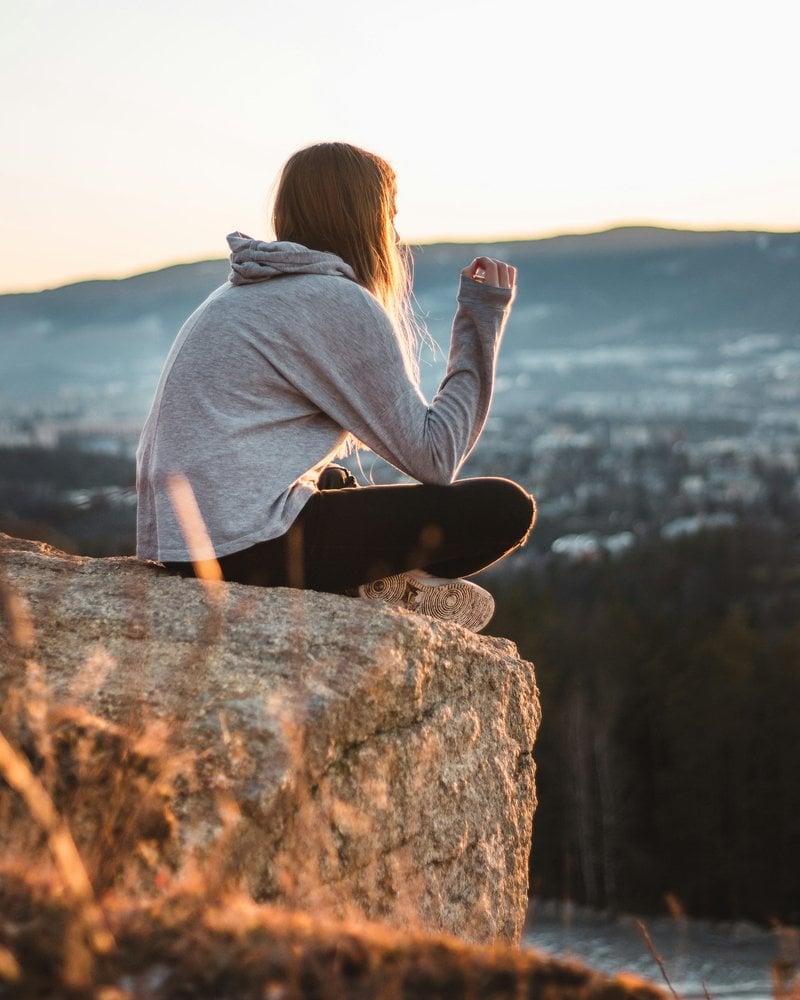 Woman wearing grey hooded jacket sitting on the stone photo ...
