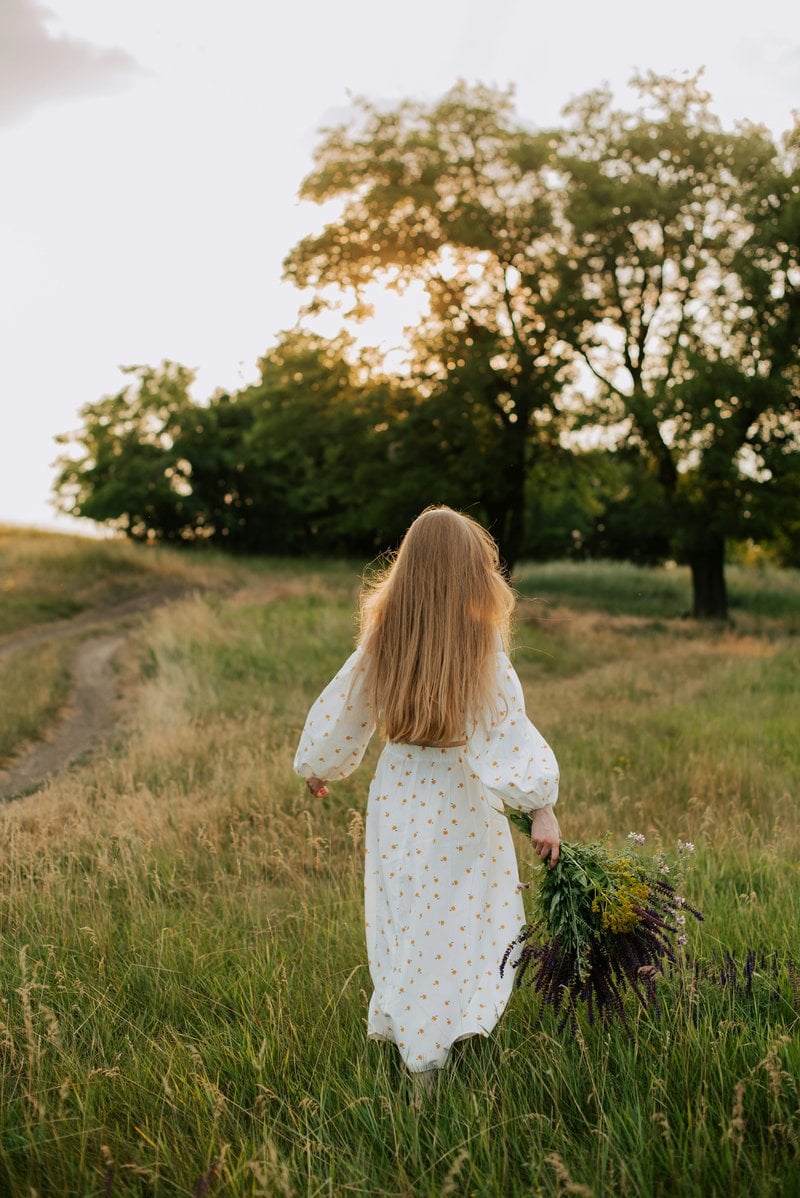A little girl in a white dress walking through a field - Free Photo on  Unsplash