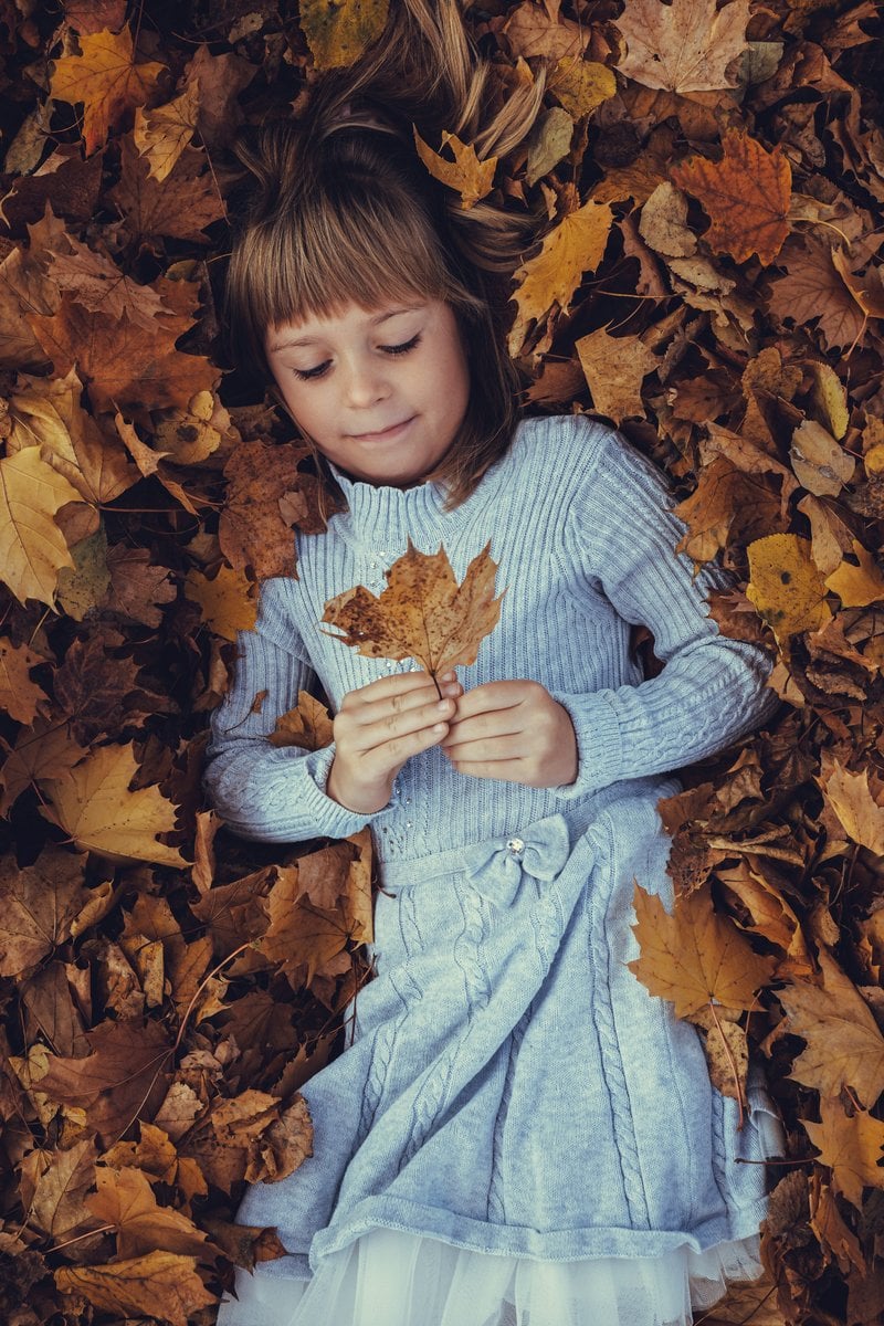 A little girl laying in a pile of leaves - Free Photo on ...